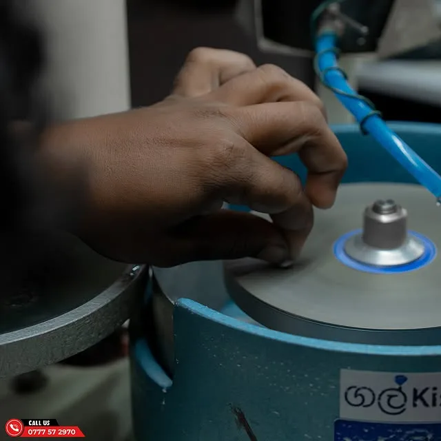 A student's hands guiding a rough stone on a lapidary cutting wheel in the CAGS lab